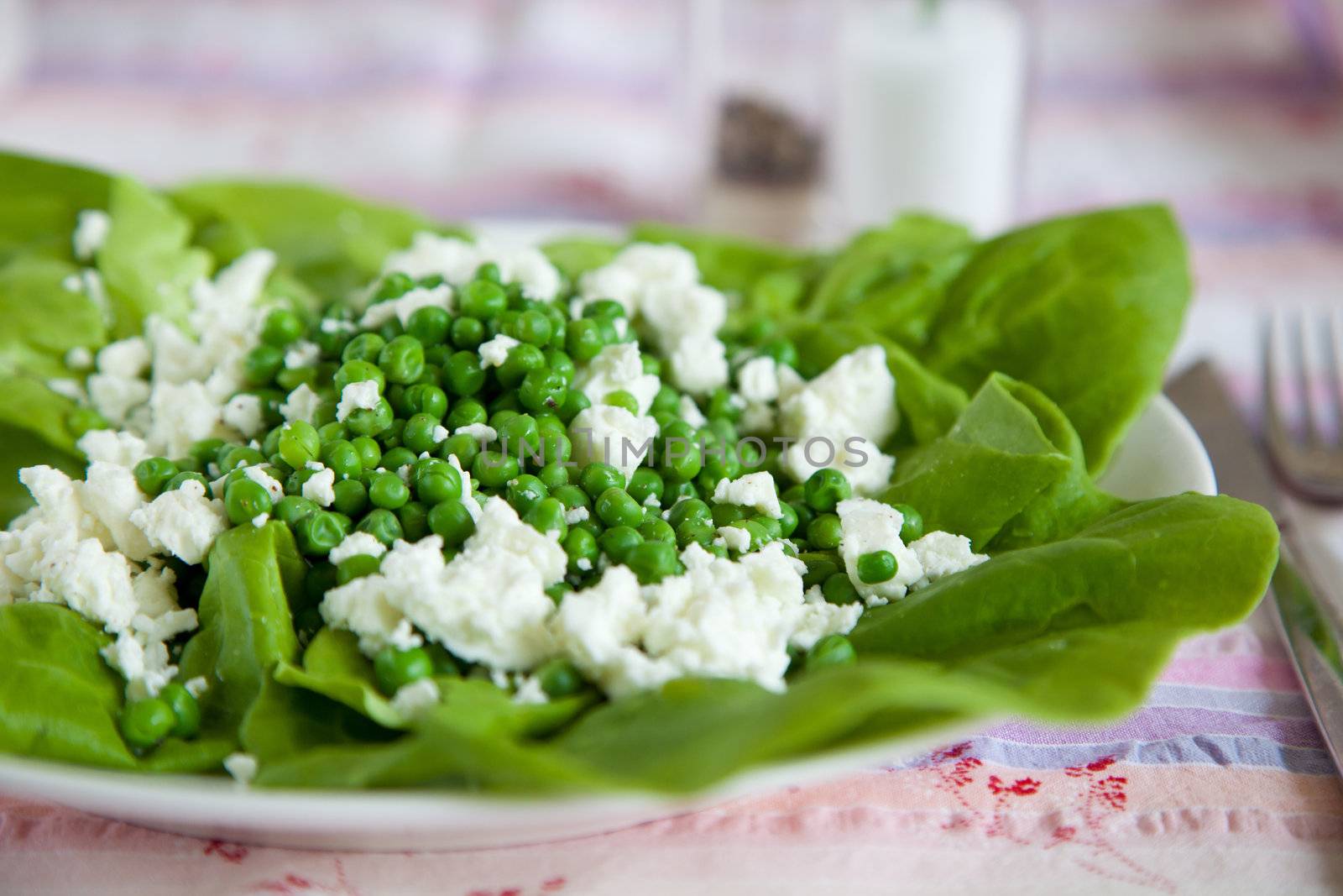 Fresh salad with peas, feta and salad leaves tossed with olive oil