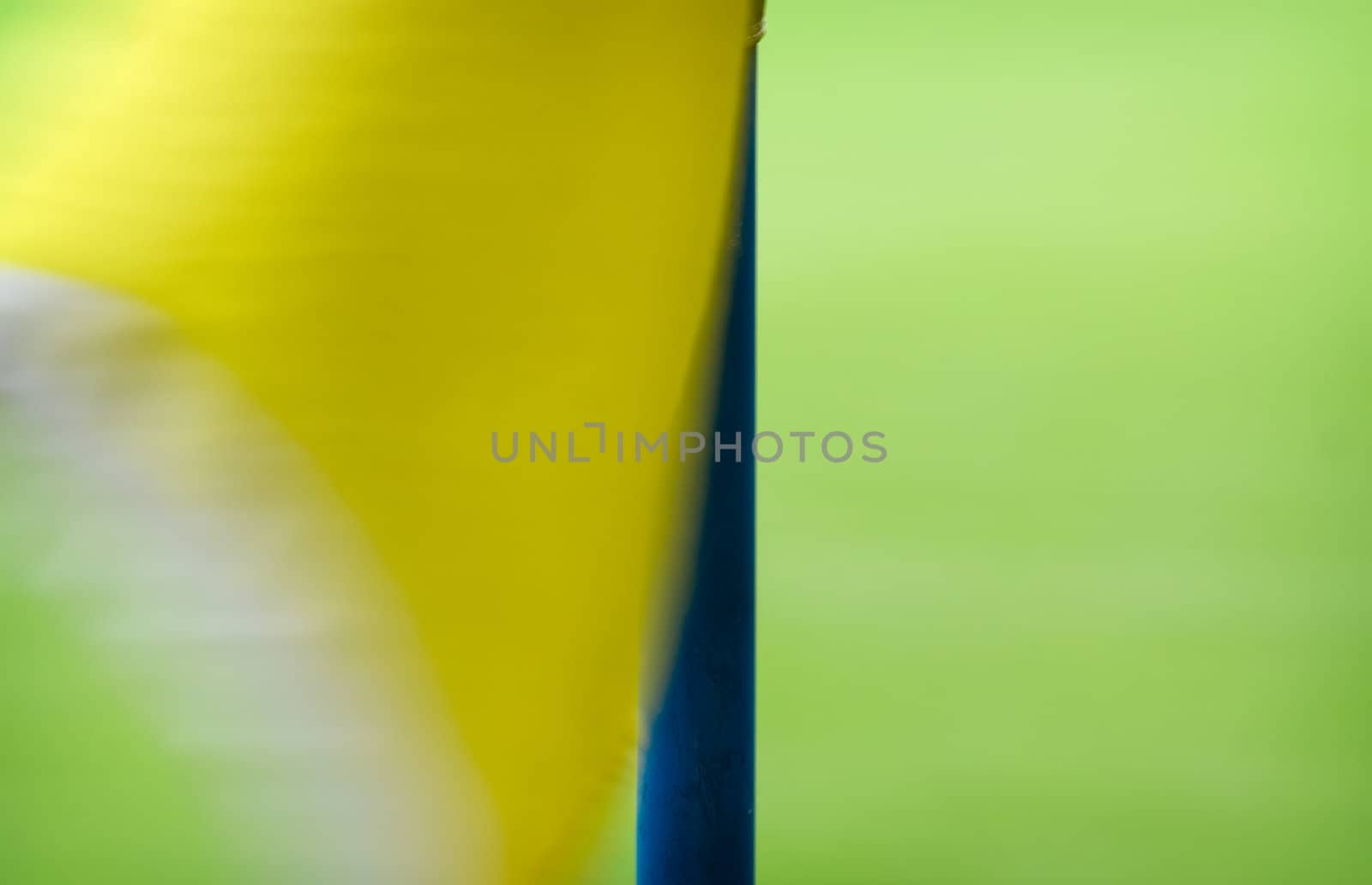 Yellow corner flag on a football field waving in the wind.