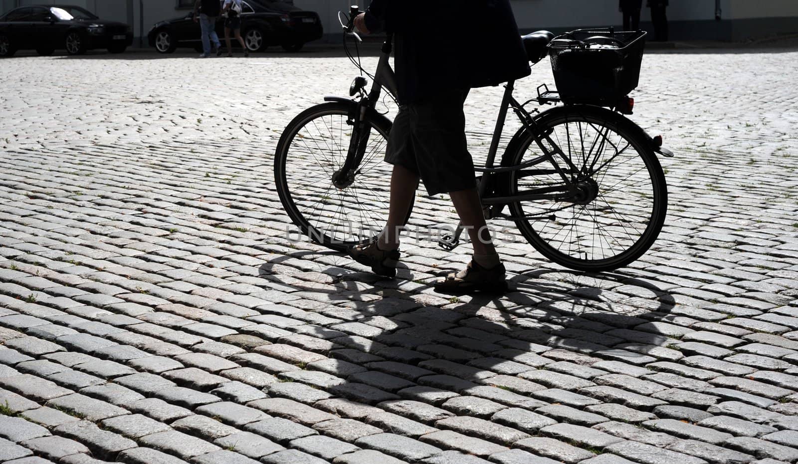 Man walking his bicycle on an old cobblestone road
