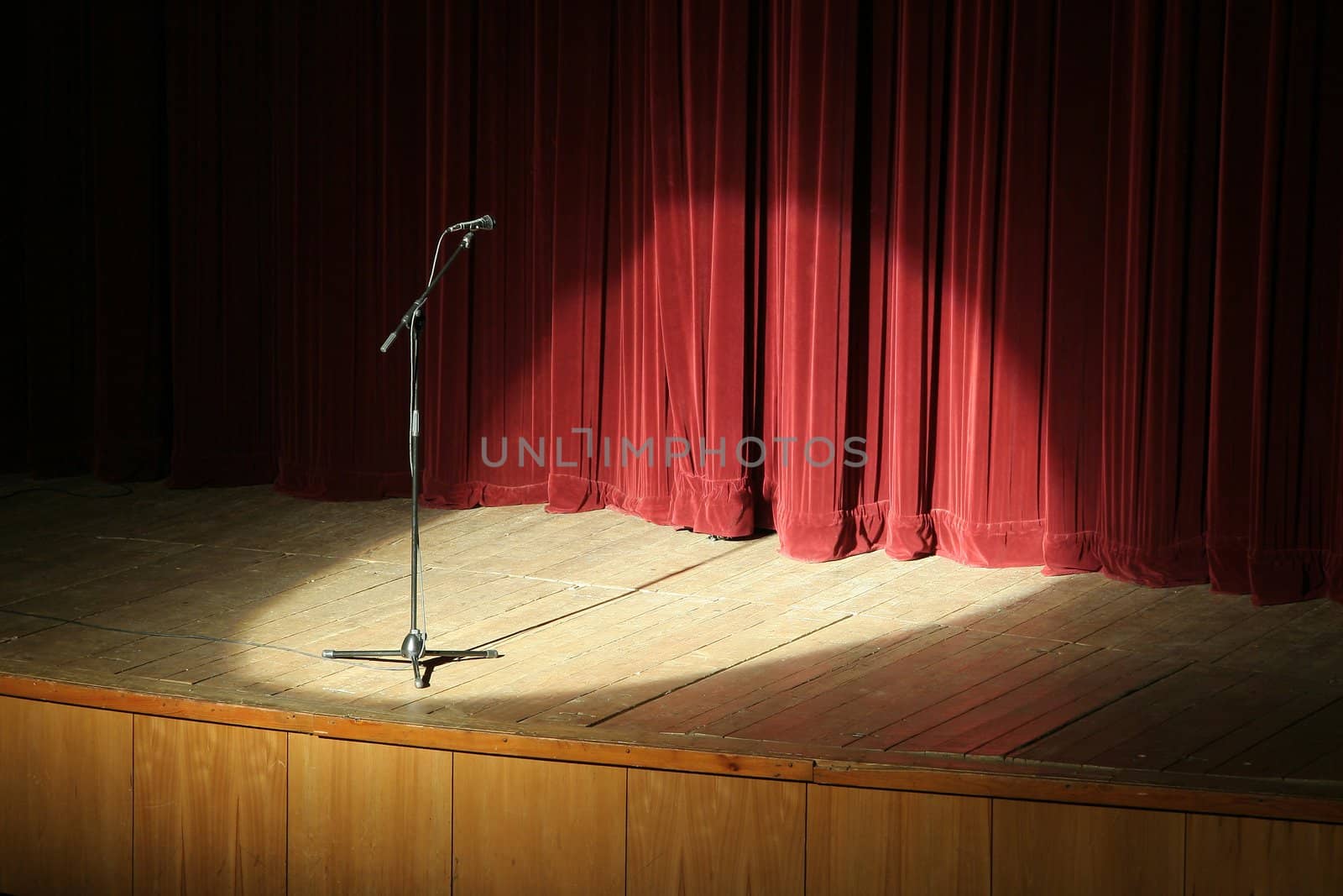 microphone on wooden stage, red curtain in background, spot light