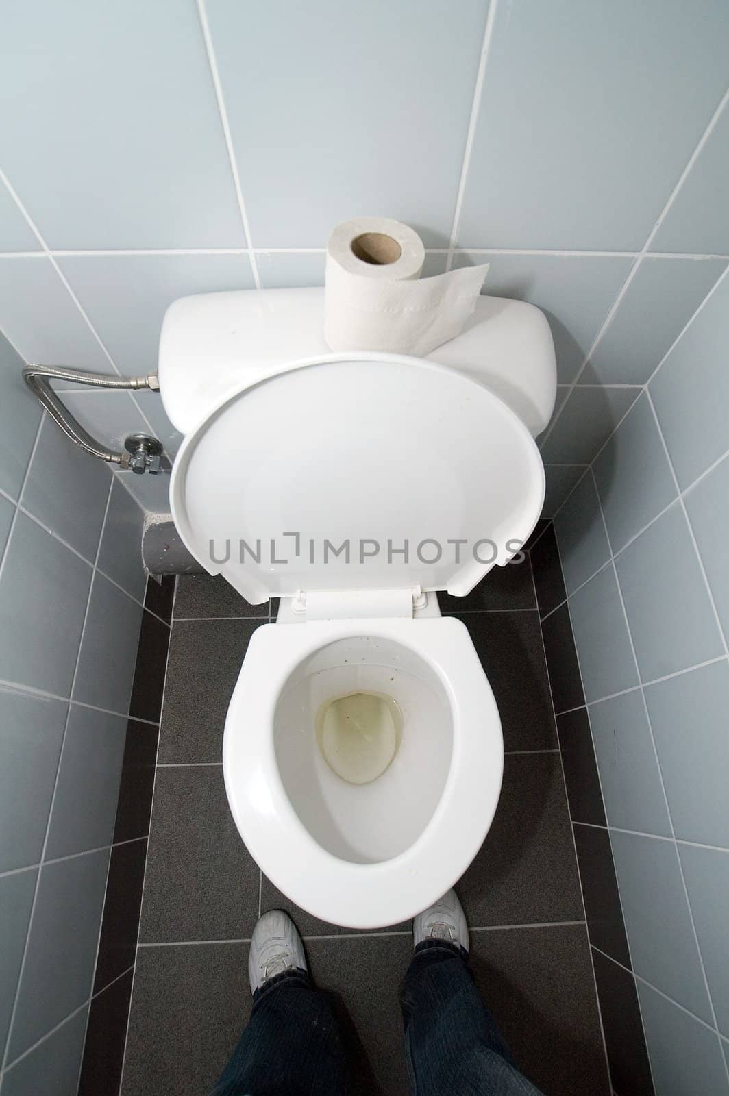 empty clean white toilet and toilet paper on it, man standing in front of it, 