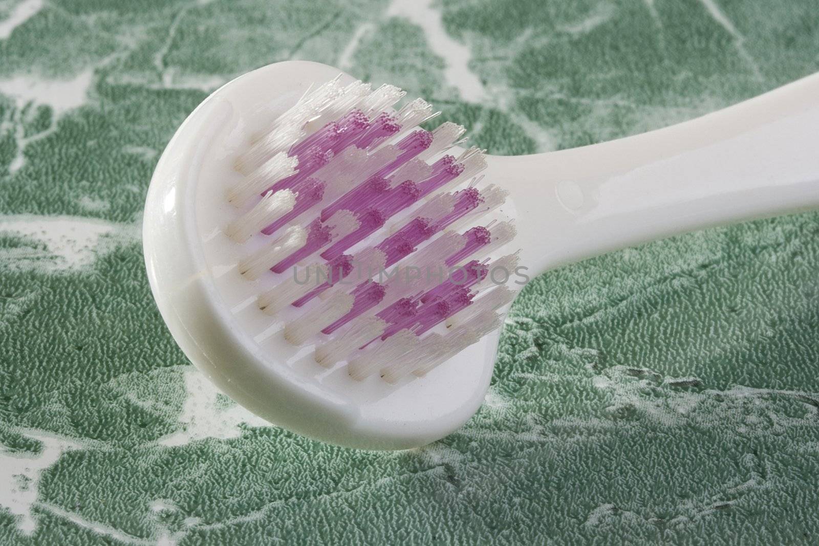 White tongue brush on the green countertop.