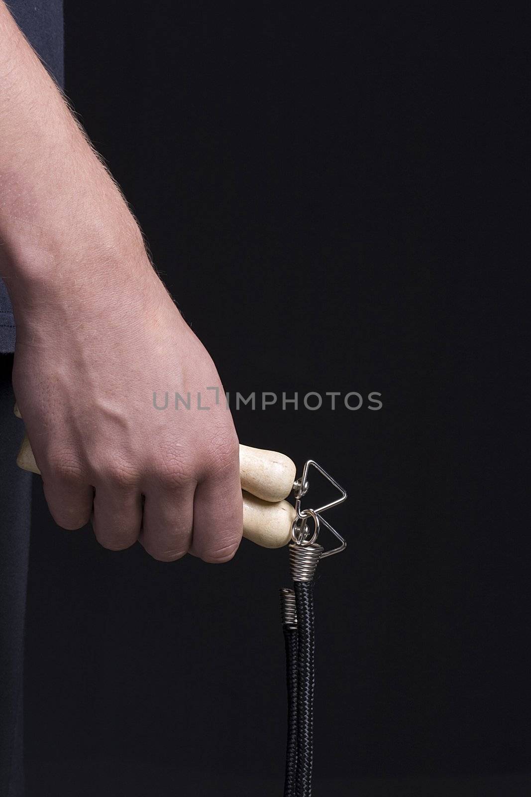 Human hand holding a jump rope on a black background.