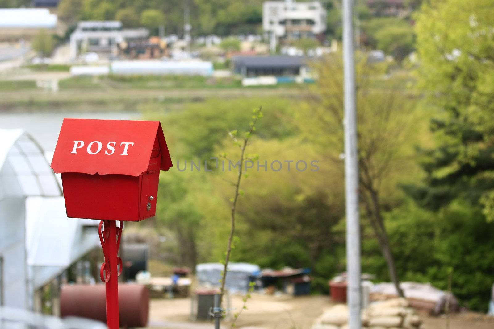 Red colored mailbox on farm with post text