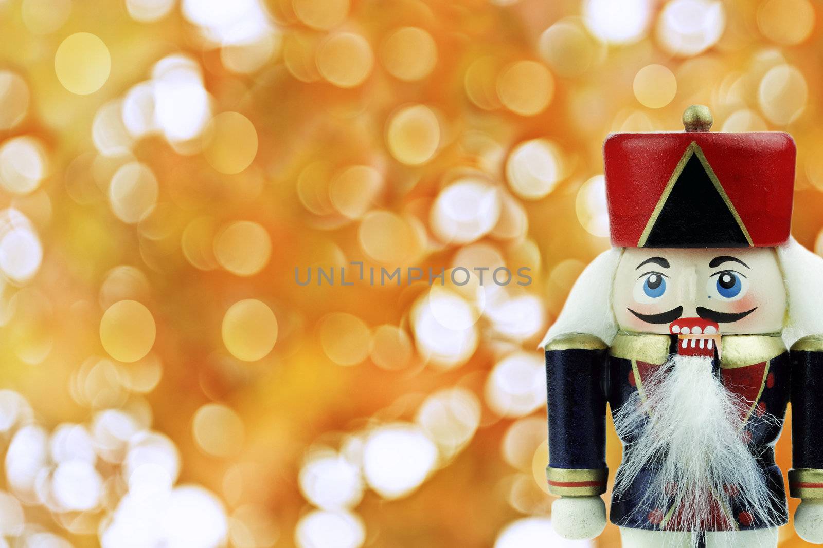 Wooden Nutcracker against a background of golden holiday lights .