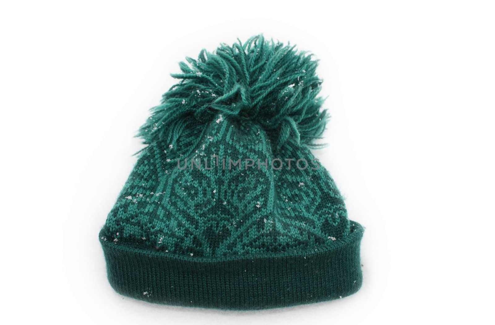 Warm woolen hat on white background covered with snowflakes