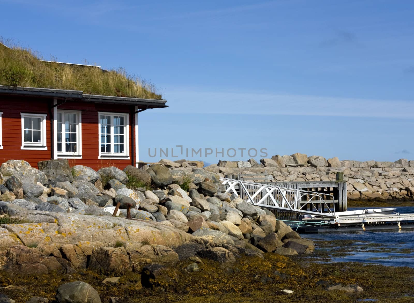 Red house by the sea, with a private harbour and boat.