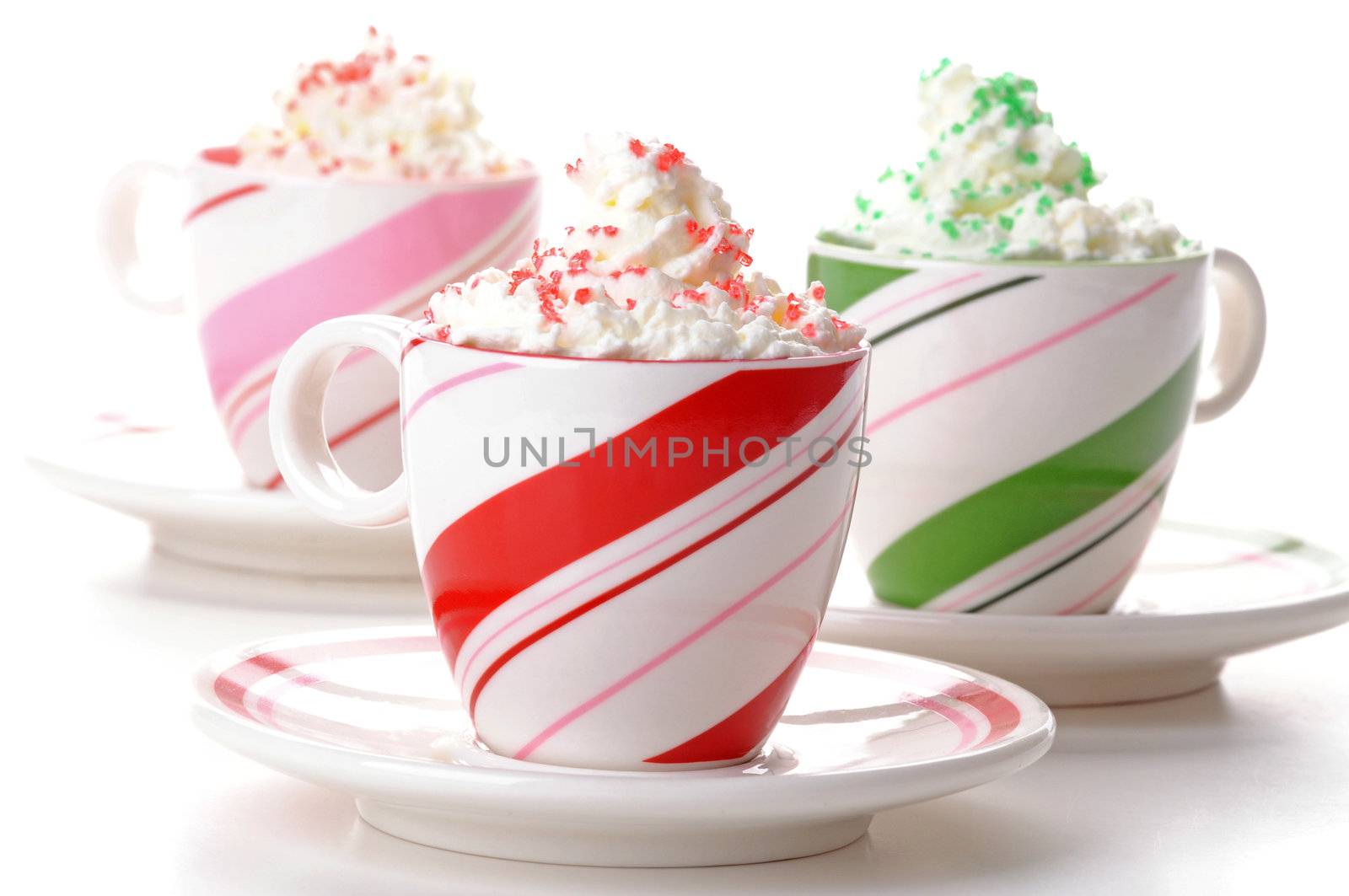 Three colorful mugs of festive drinks with whipped cream.