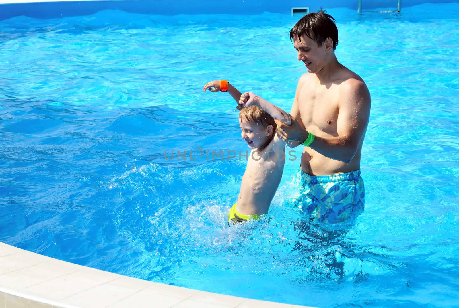  father and son having fun in water pool 