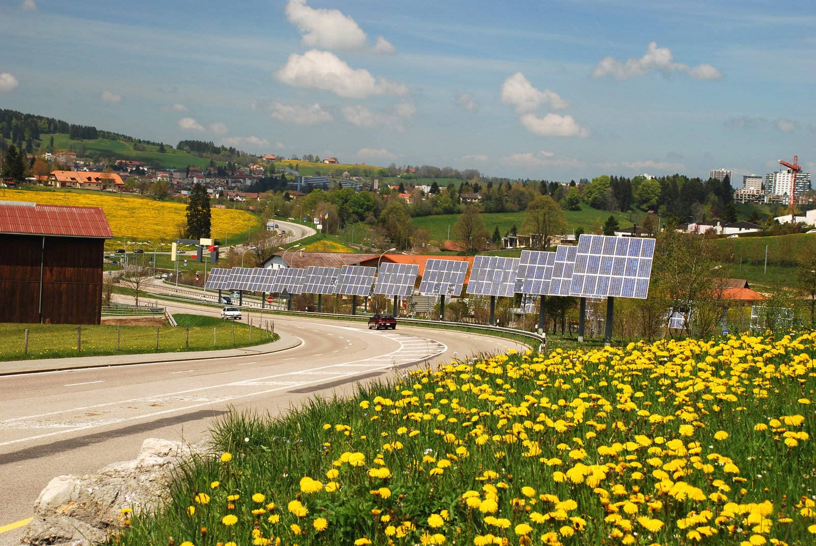 Solar cells along the roat to  Le-Chaux-de-Fonds city, yellow flowers of dandelions at foreground