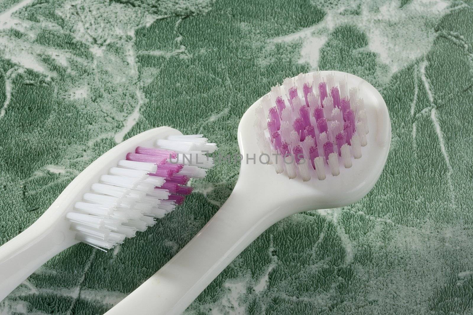 Tooth brush and a tongue brush on the green countertop.