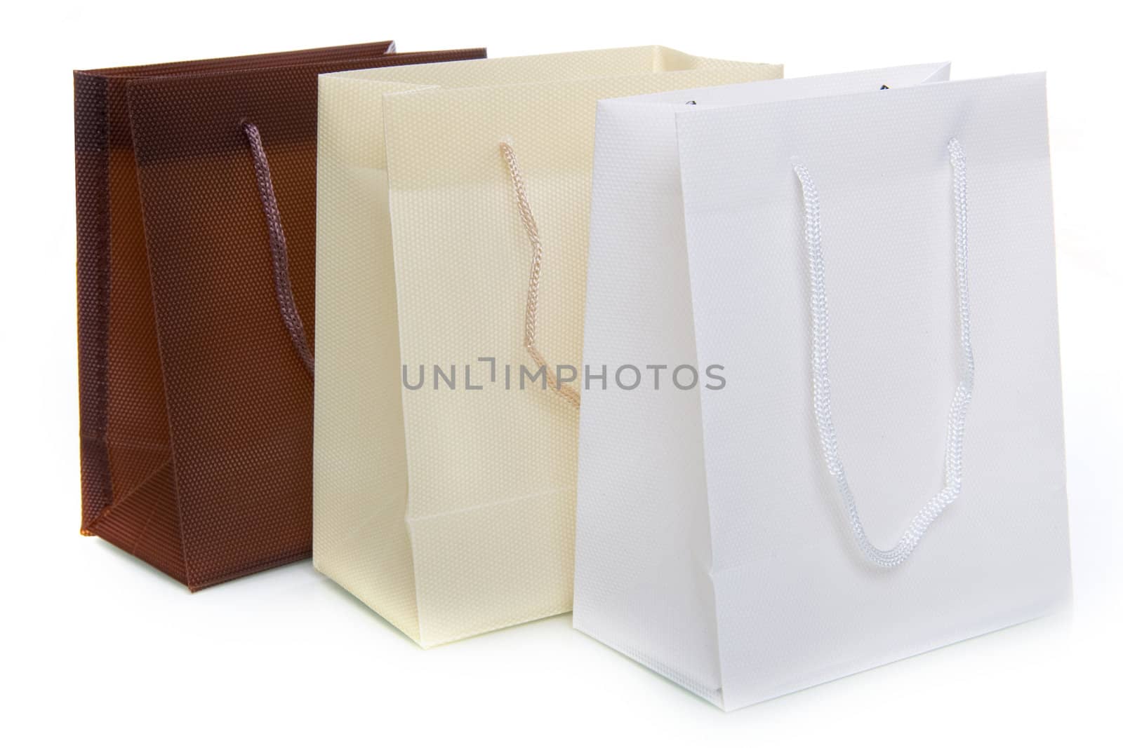 three bags, a brown, a white and a creme one, on a white background