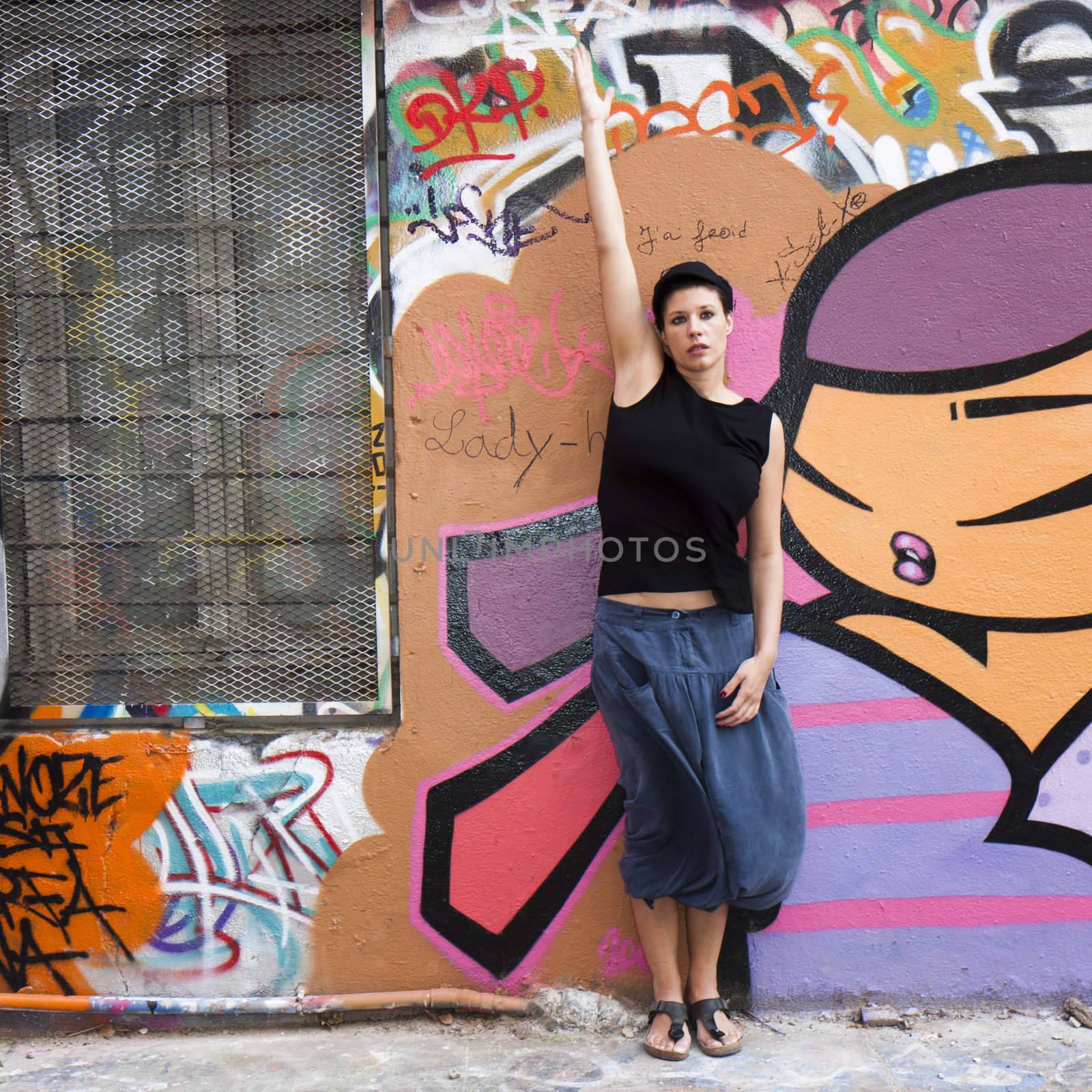 a woman stretches before a wall covered in graffiti