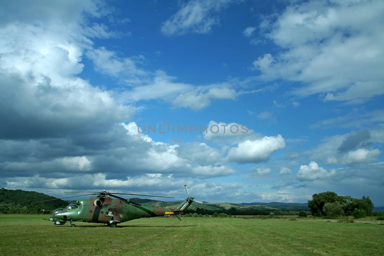 military helicopter on grass ground, cloudy sky