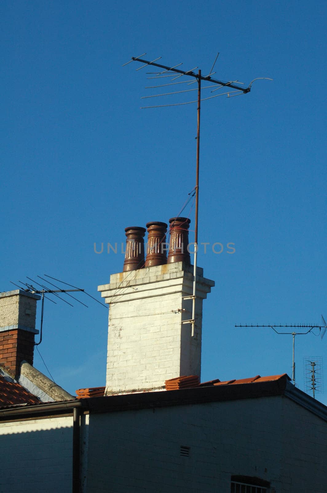 roof detail, old chimney made of bricks, four televison antennas 