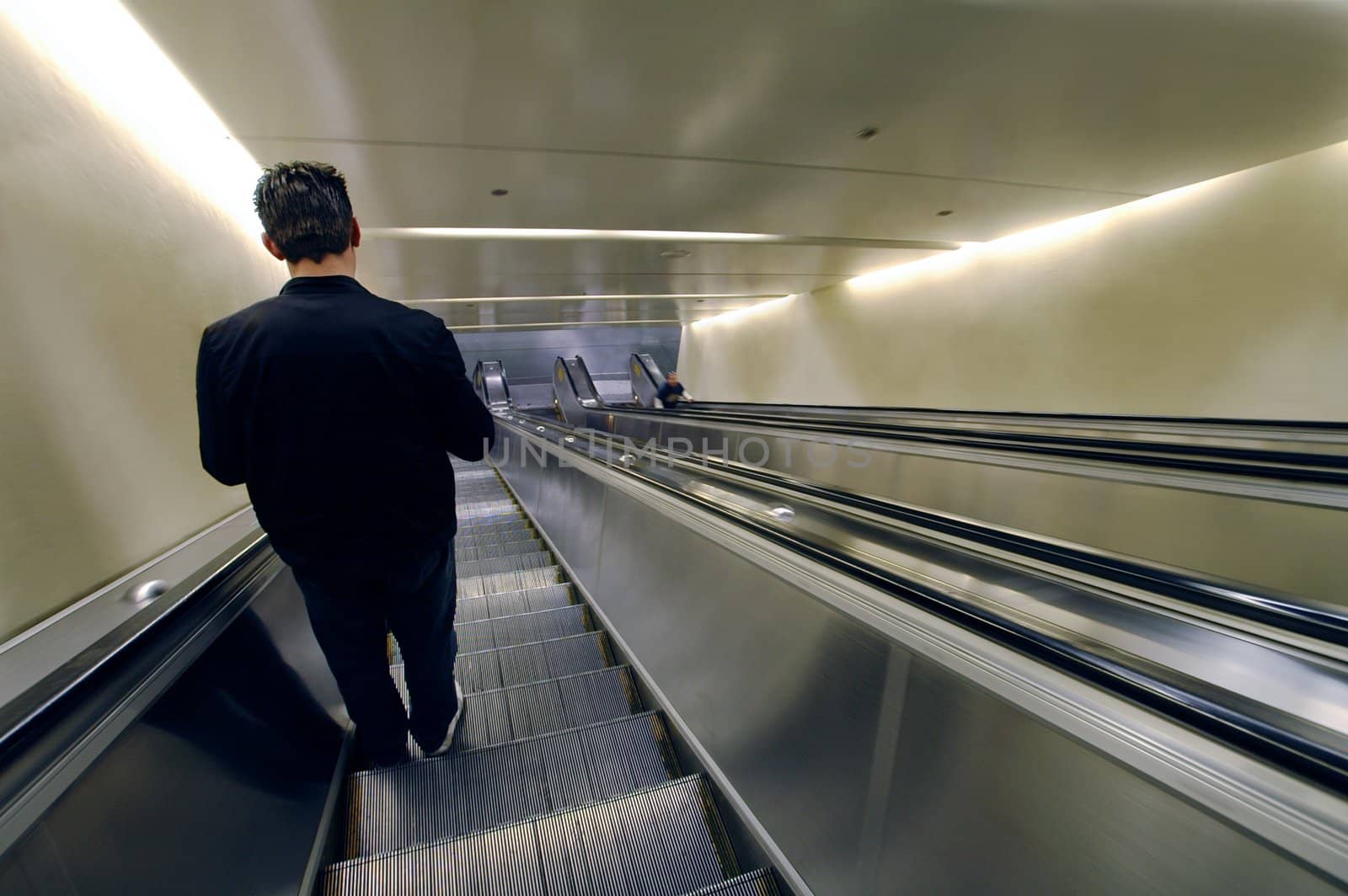 solitary man going down on an escalator (retouched)