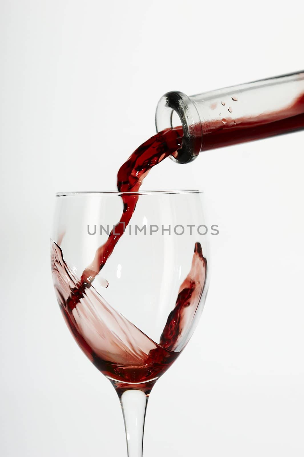 Flowing red wine from bottle to glass