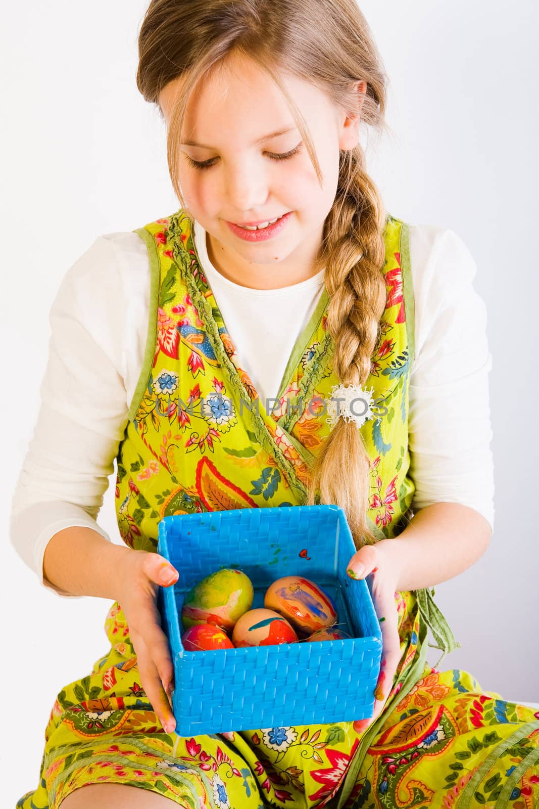 Studio portrait of a young blond girl who is shwong a box full of easter eggs