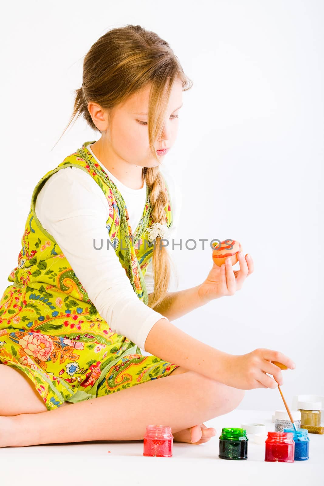 Studio portrait of a young blond girl painting eggs for easter