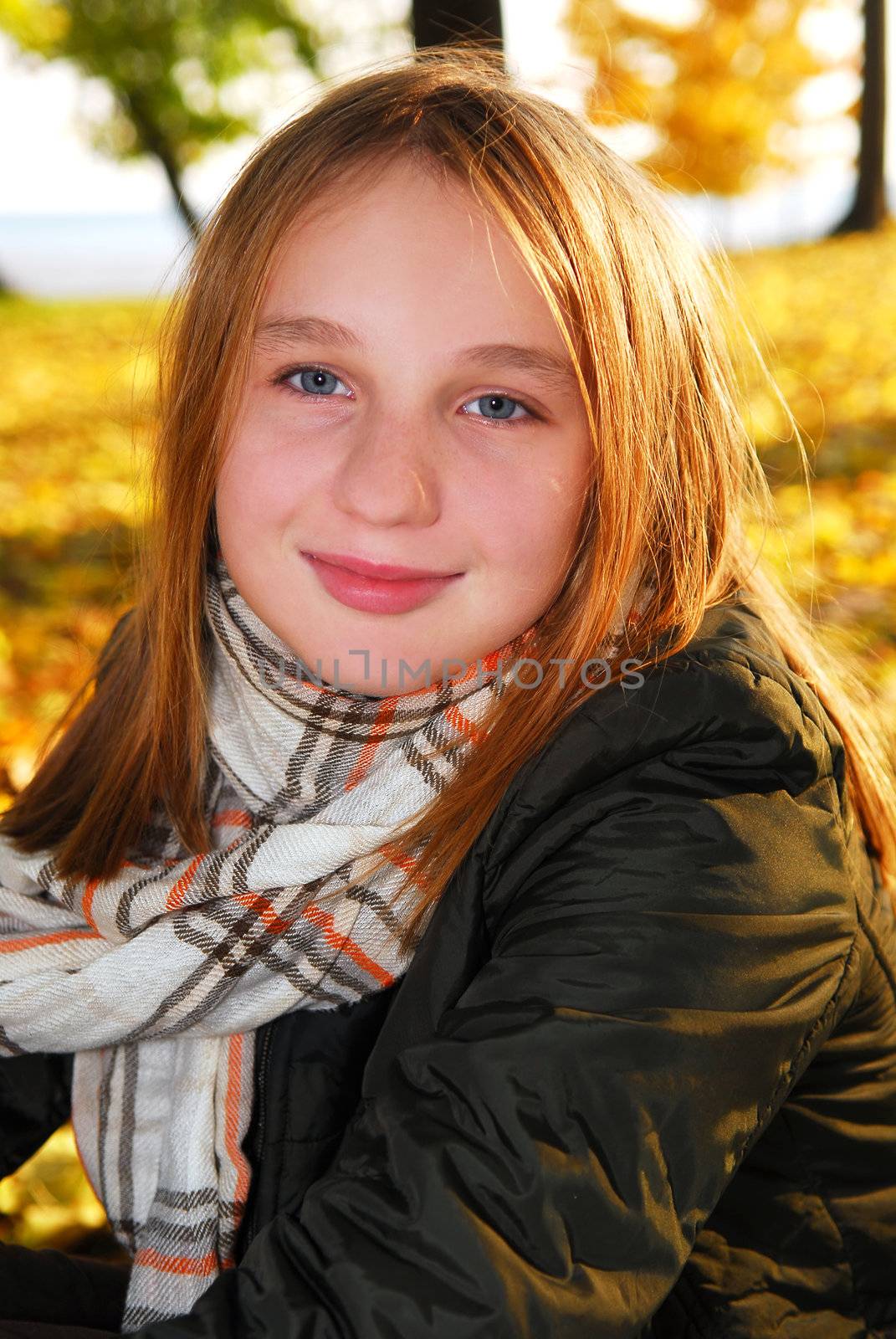 Portrait of a beautiful teenage girl in a fall park with fallen leaves
