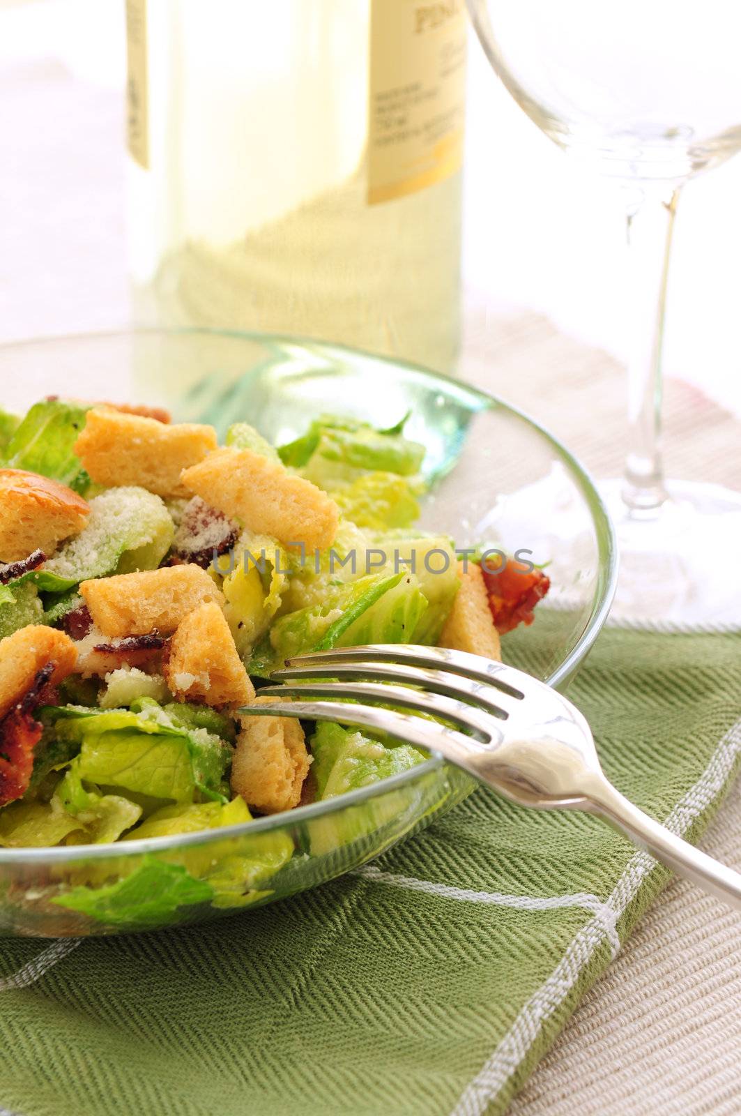 Caesar salad served in a glass bowl and white wine