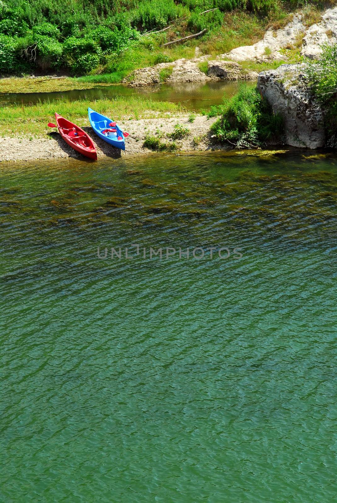 Kayaks on river bank by elenathewise
