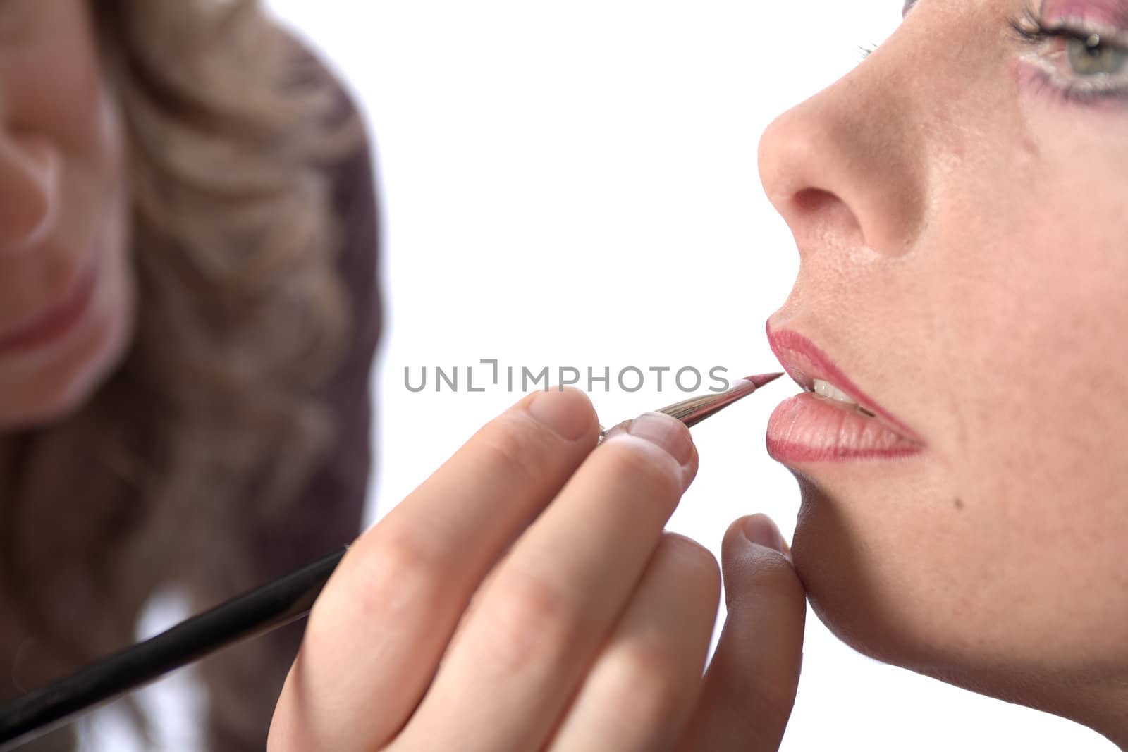 Studio image of make-up artist at work applying lipstick