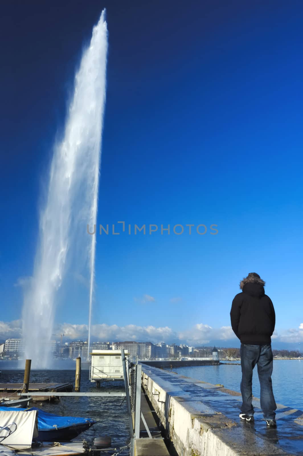The famous Jet d'Eau fountain in Geneva, Switzerland with a figure walking towards it.