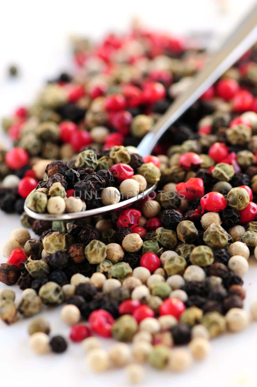 Mixed assorted peppercorns on white background macro