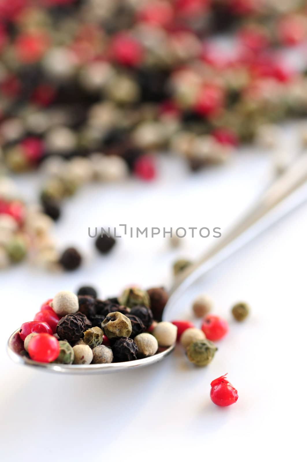 Mixed assorted peppercorns on white background macro