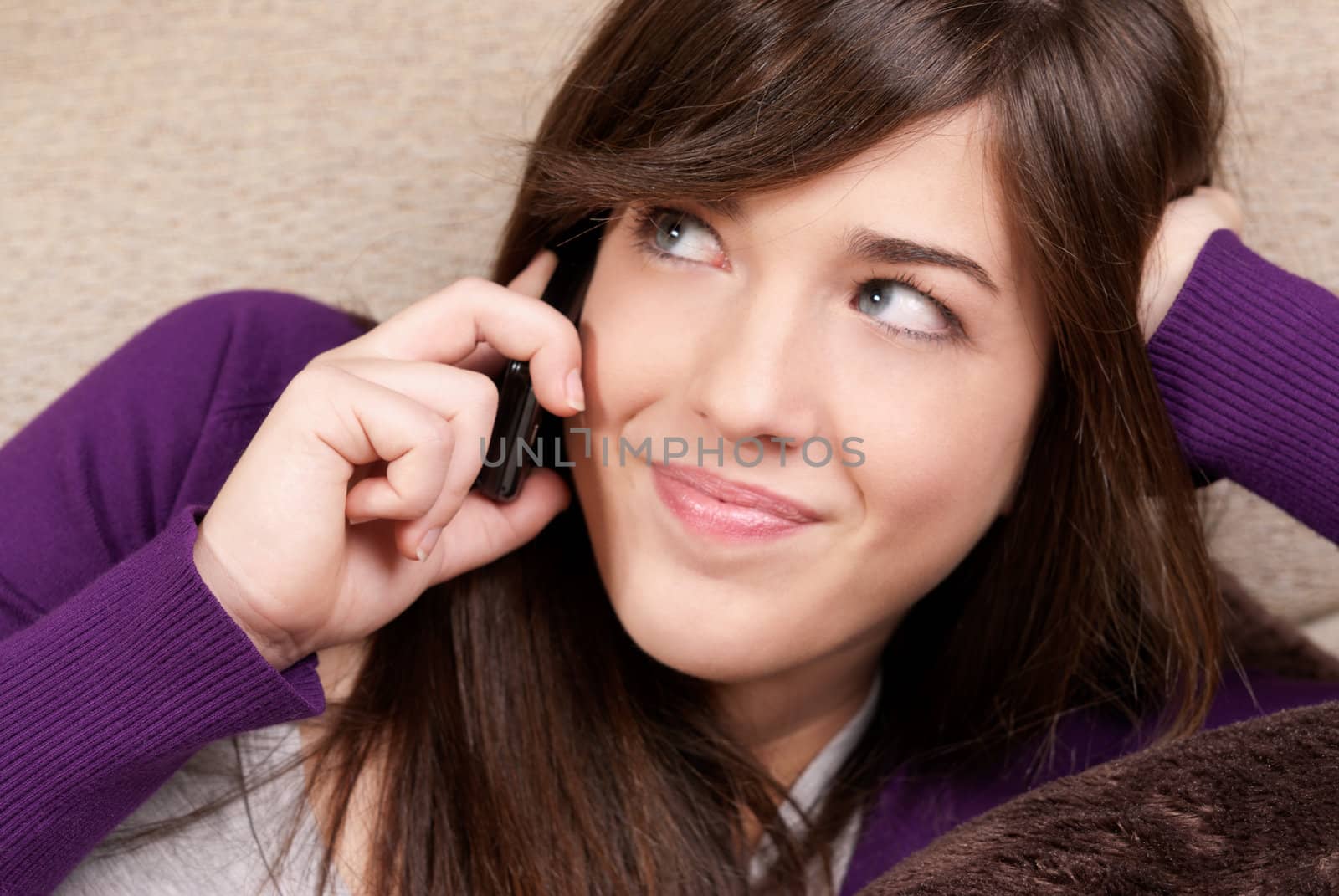 Young female talking by telephone smiling lying on couch close-up