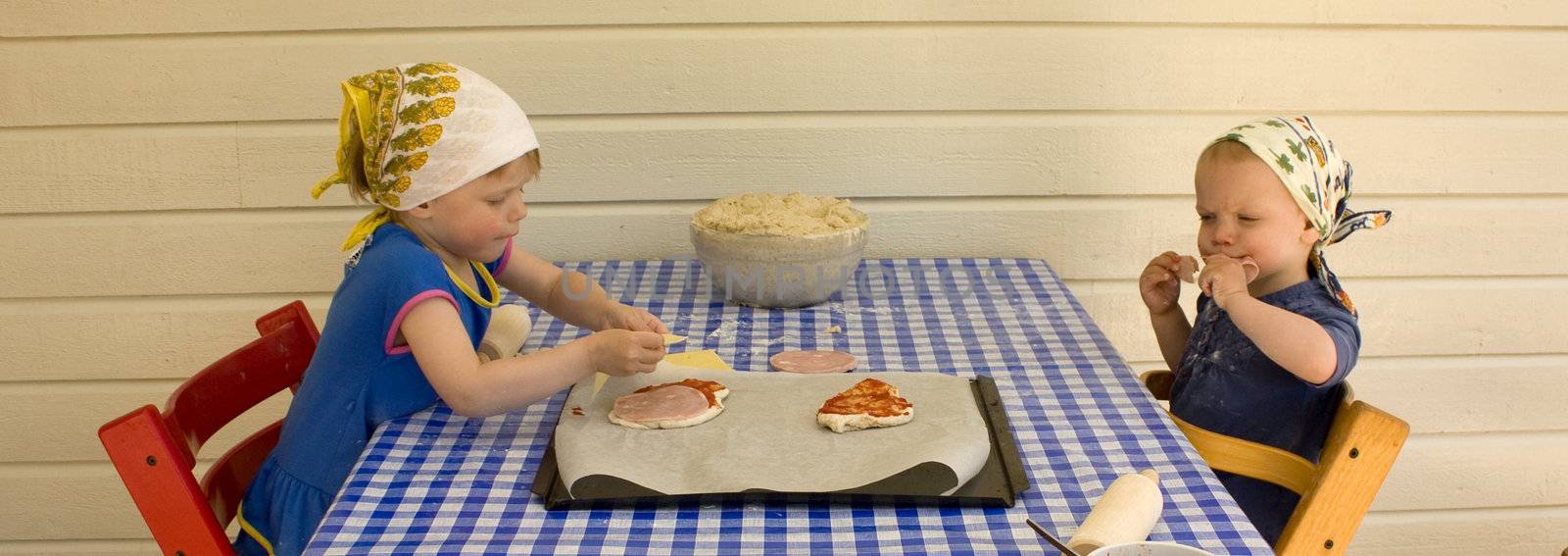Small girls (2 and 3 years old) baking pizza