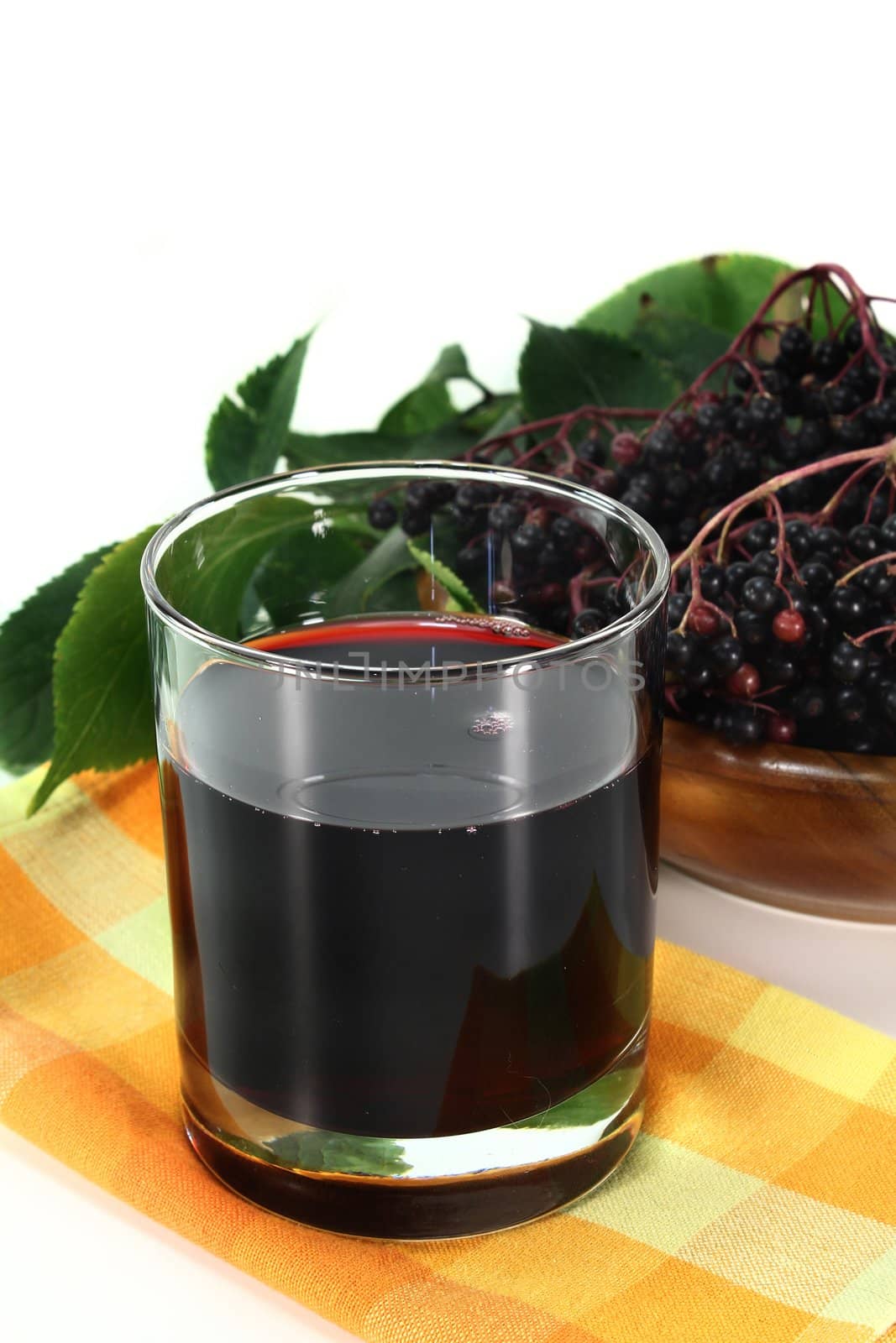 a glass of elderberry juice and fresh elderberries