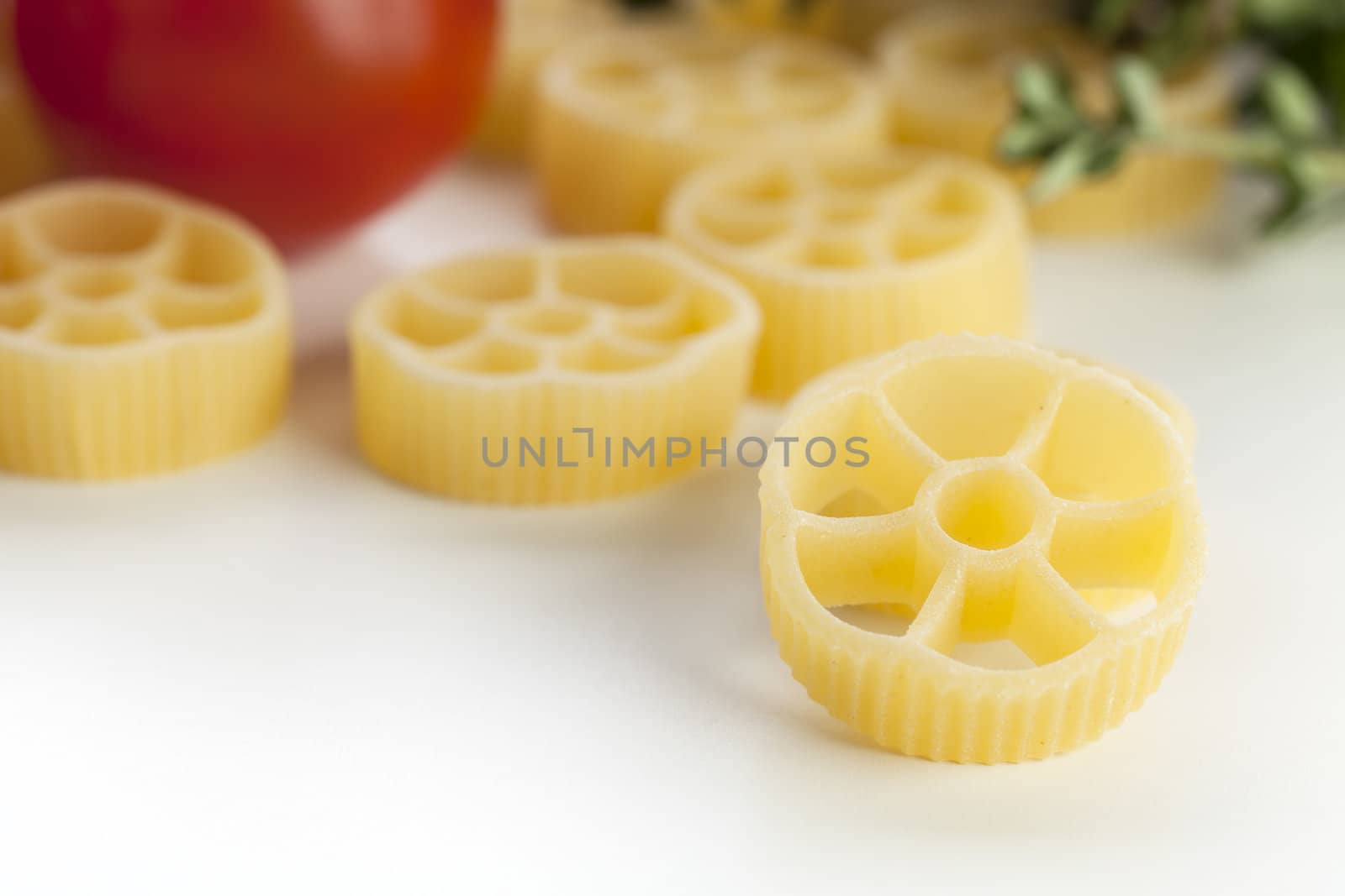 Close up of dried rotelle pasta with other ingredients in the background.