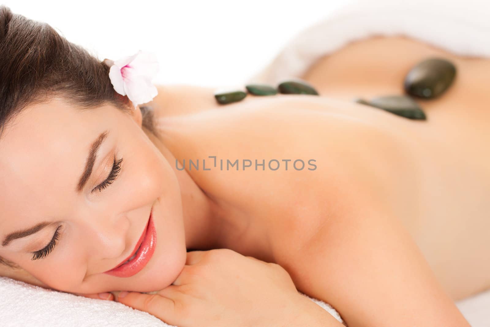 Isolated portrait of an attractive young woman getting a hot stone massage