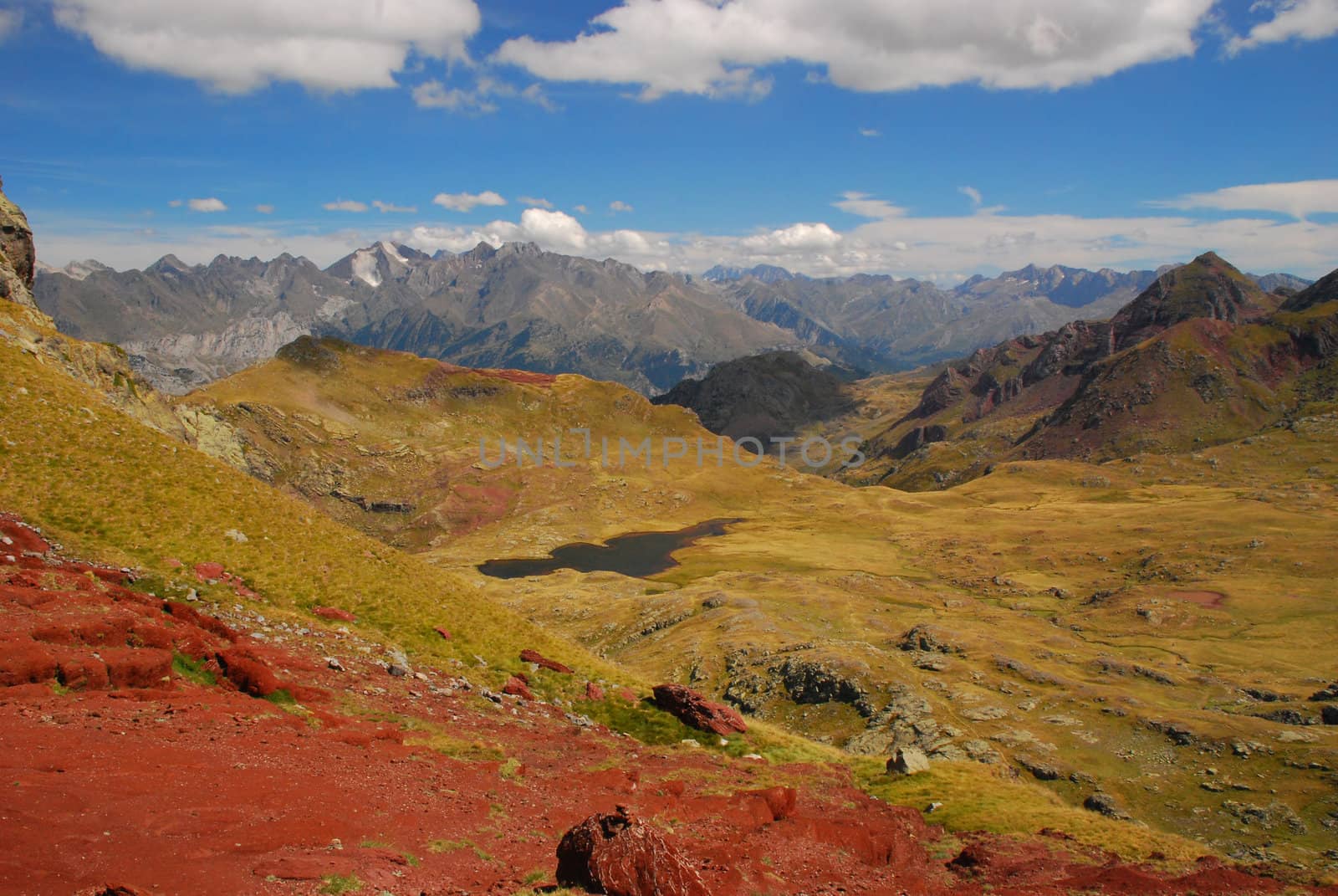 Spectacular vue at Anayet plateau, lake and Spanich Pyrenees from slope of Anayet Plateau. The red rockq at foreground, and mountain chain with famous Peak Enfer 3082 m at foreground