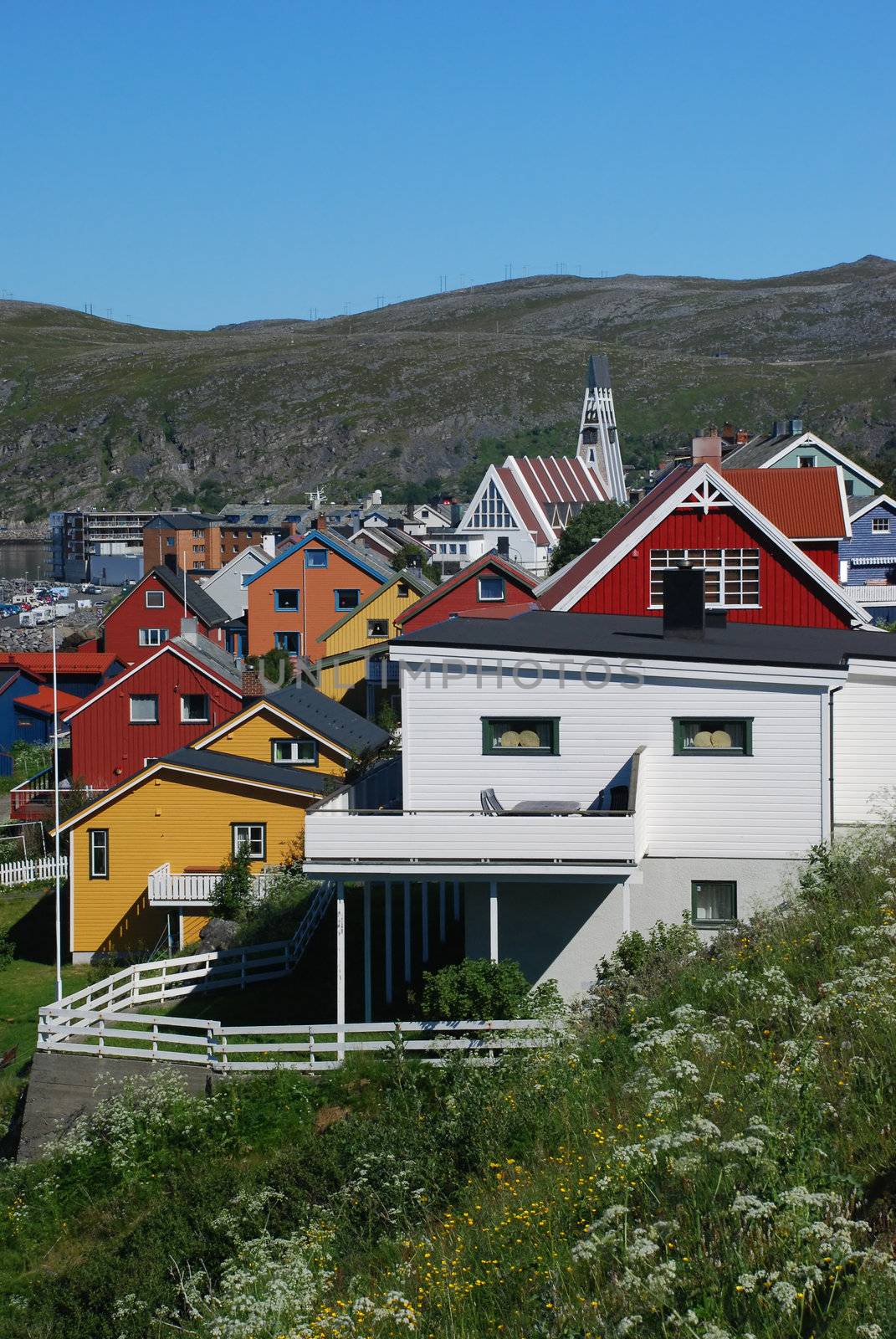 Its a cityscape of Hammerfest, claimed as a northernmost city in the world, the top of city church is behind of houses colored with different colours of Finnmark country