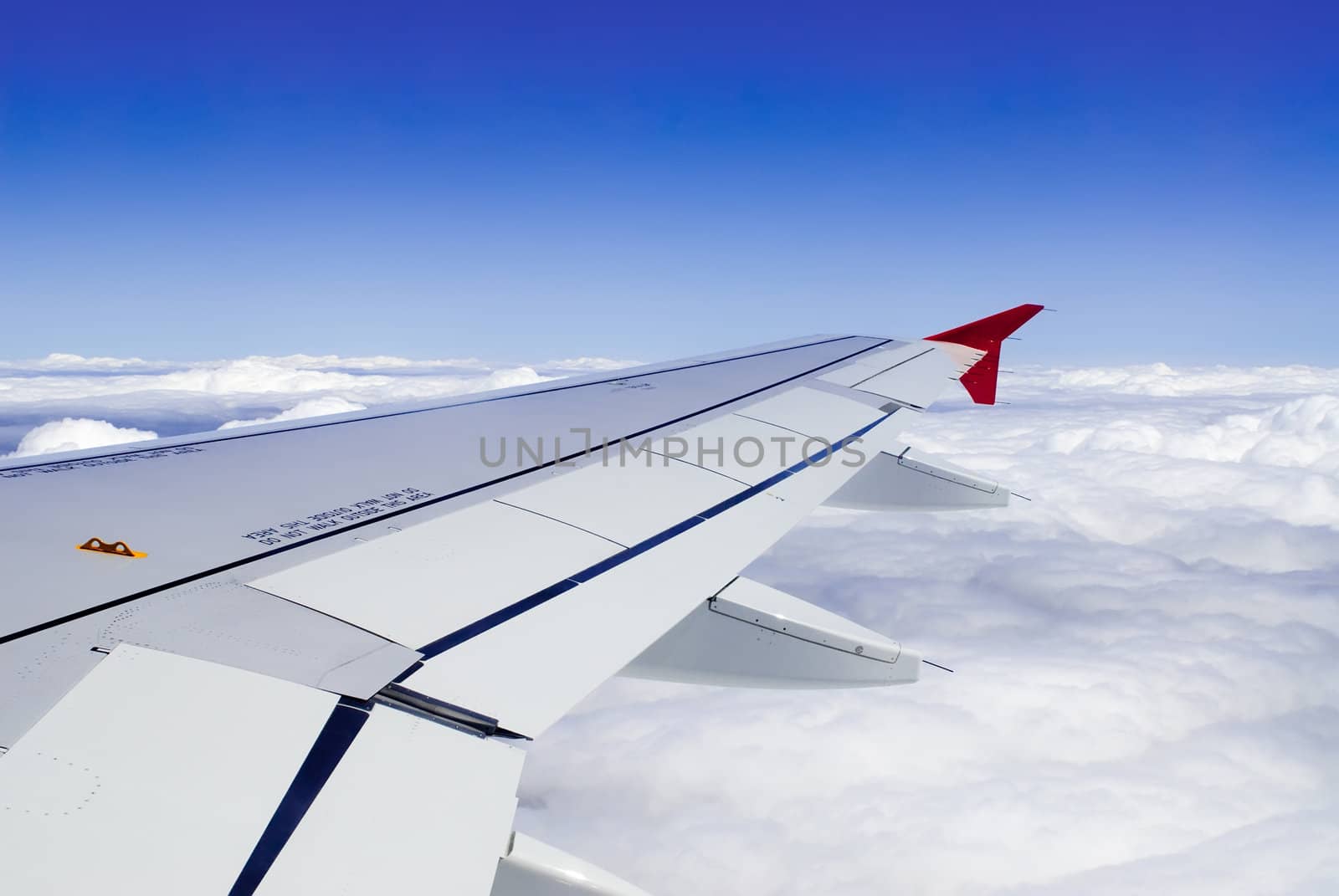 a view though an airplane window where one can see the wing and beautiful cloudy sky