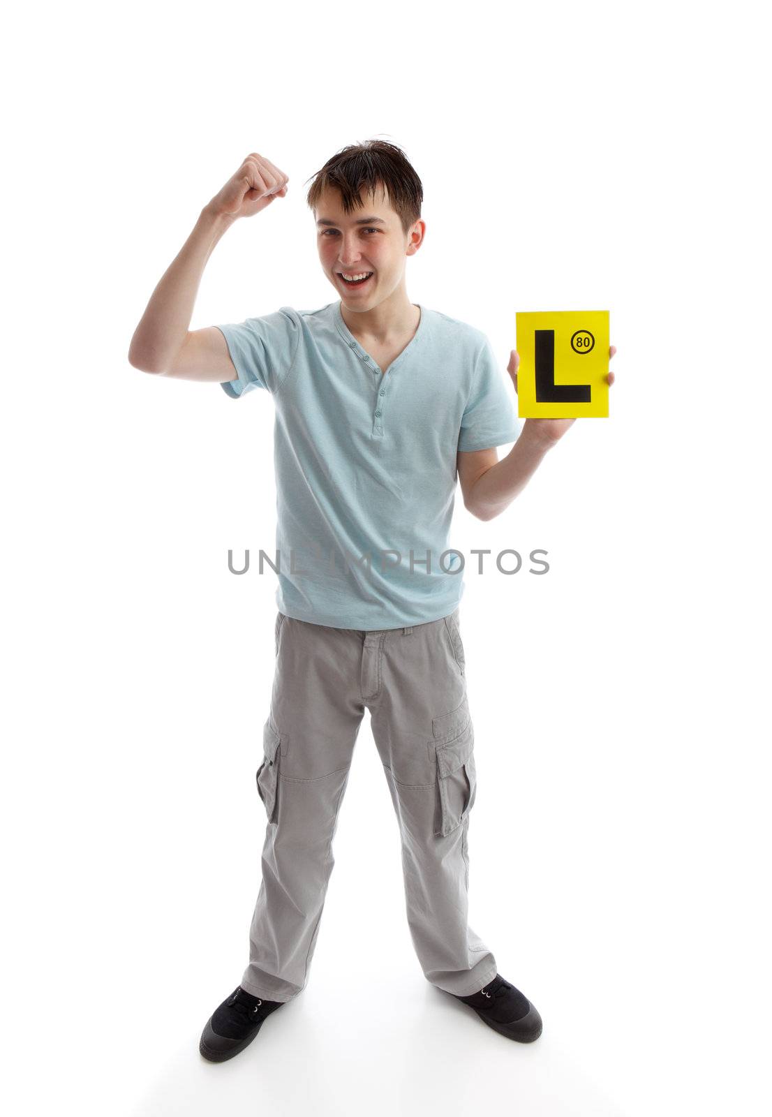 A teen boy holding his L plates (learner driving plates) and showing a fist of success.  White background. Or, plates maybe replaced with your brochure or other object.