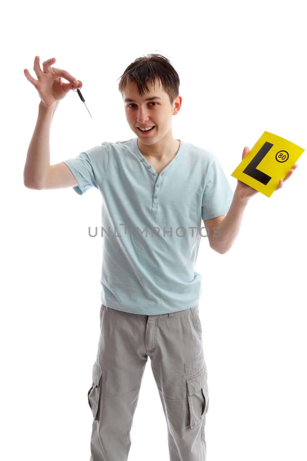 A smiling teenager holding car key and L learner plates.  White background.