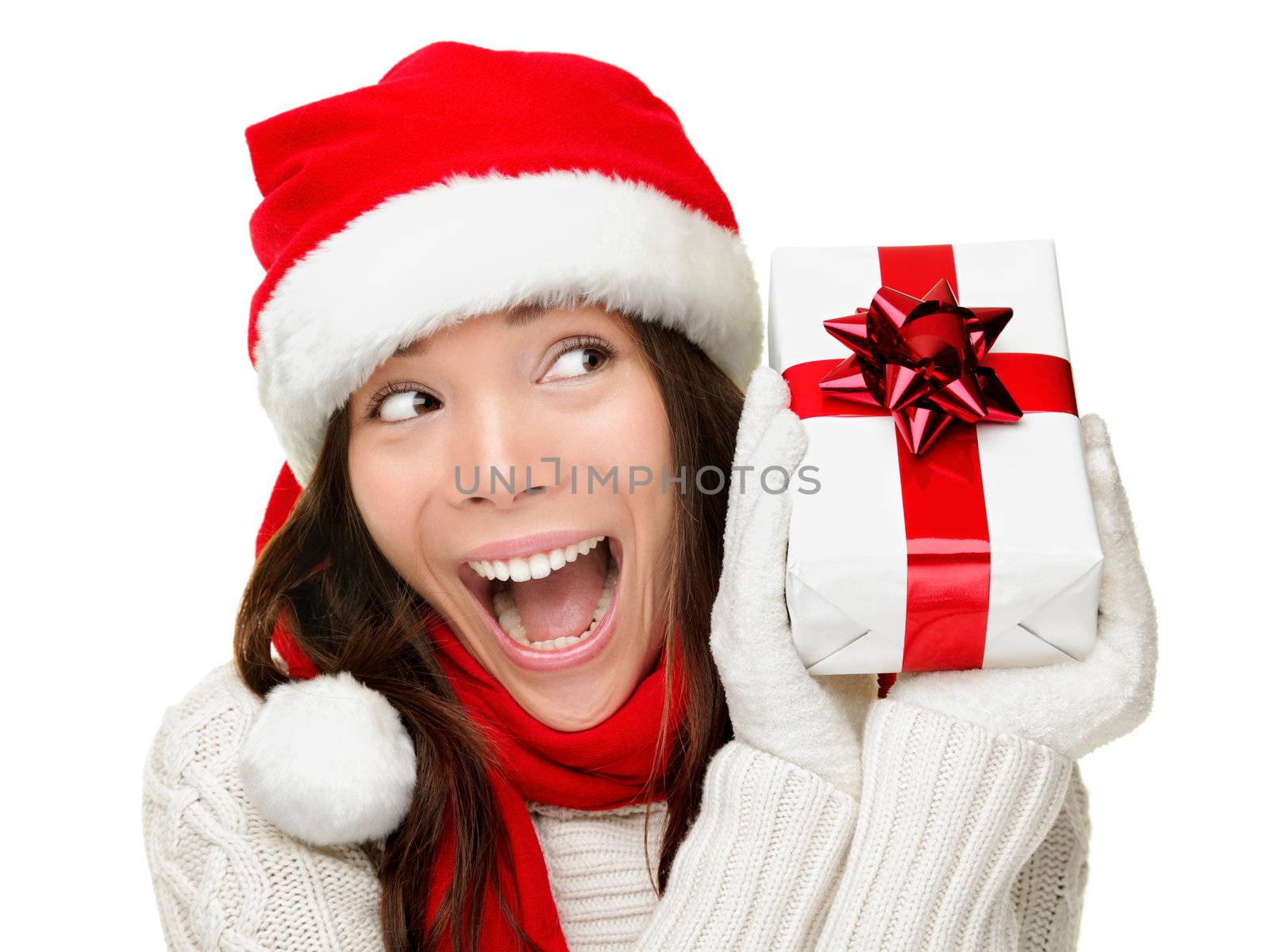 Christmas woman holding present excited. Young happy woman wearing santa hat looking to side showing Christmas gift isolated on white background. Beautiful young santa woman.