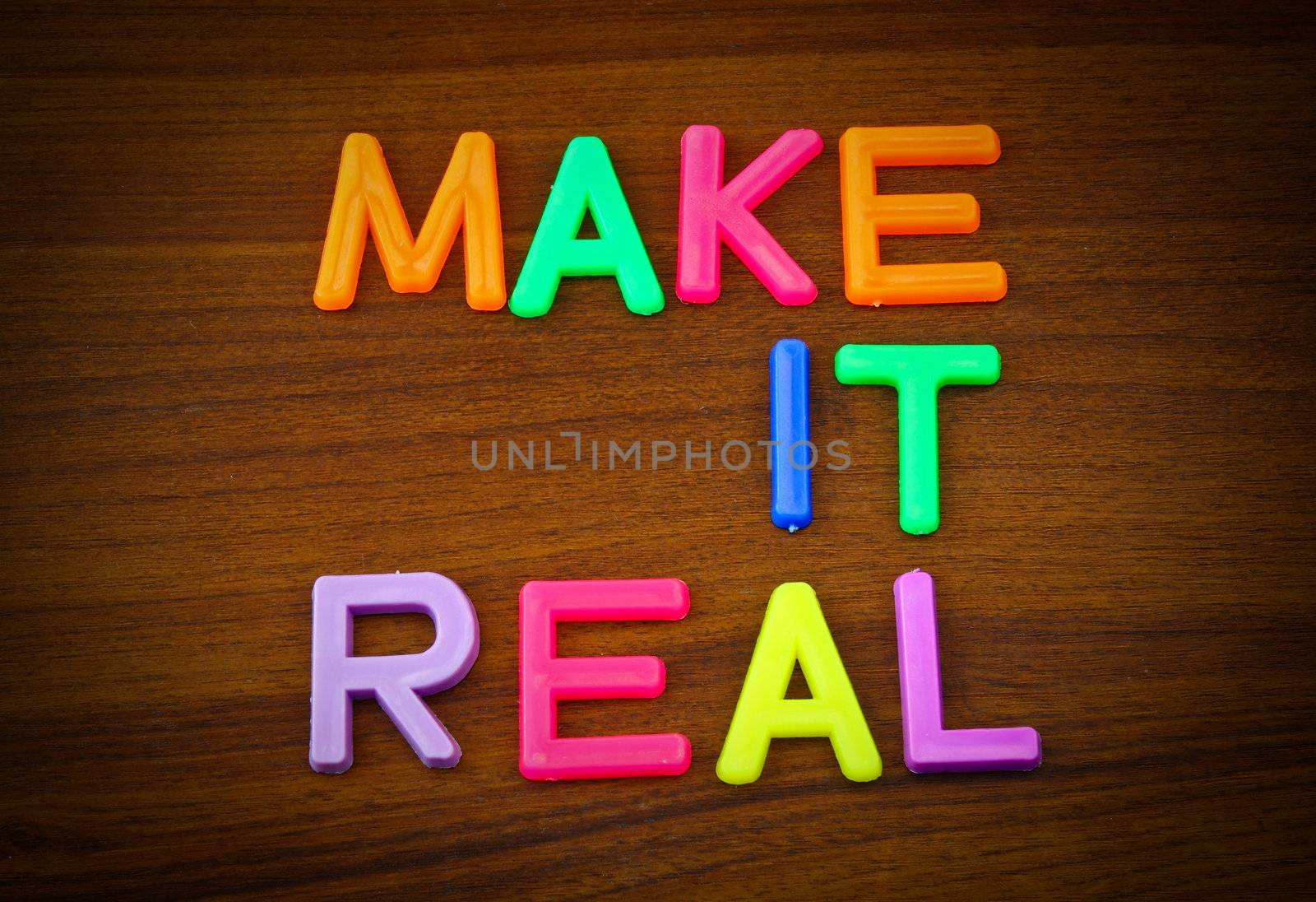 Make it real in colorful toy letters on wood background by nuchylee