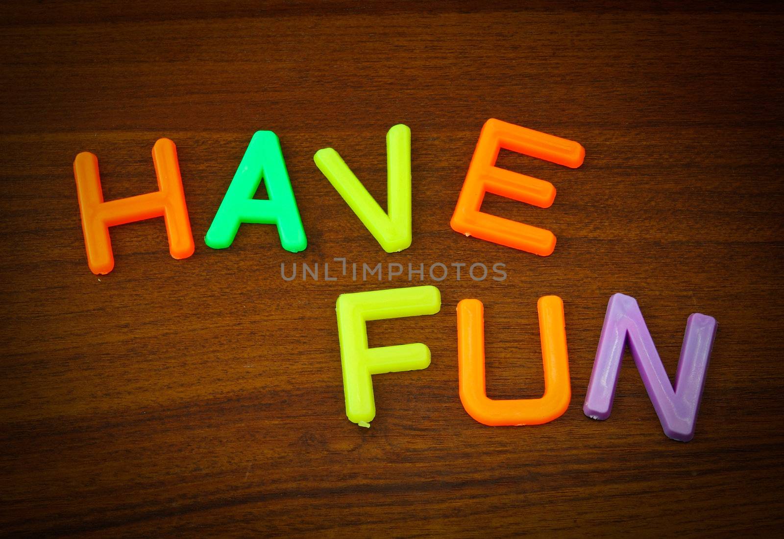 Have fun in colorful toy letters on wood background