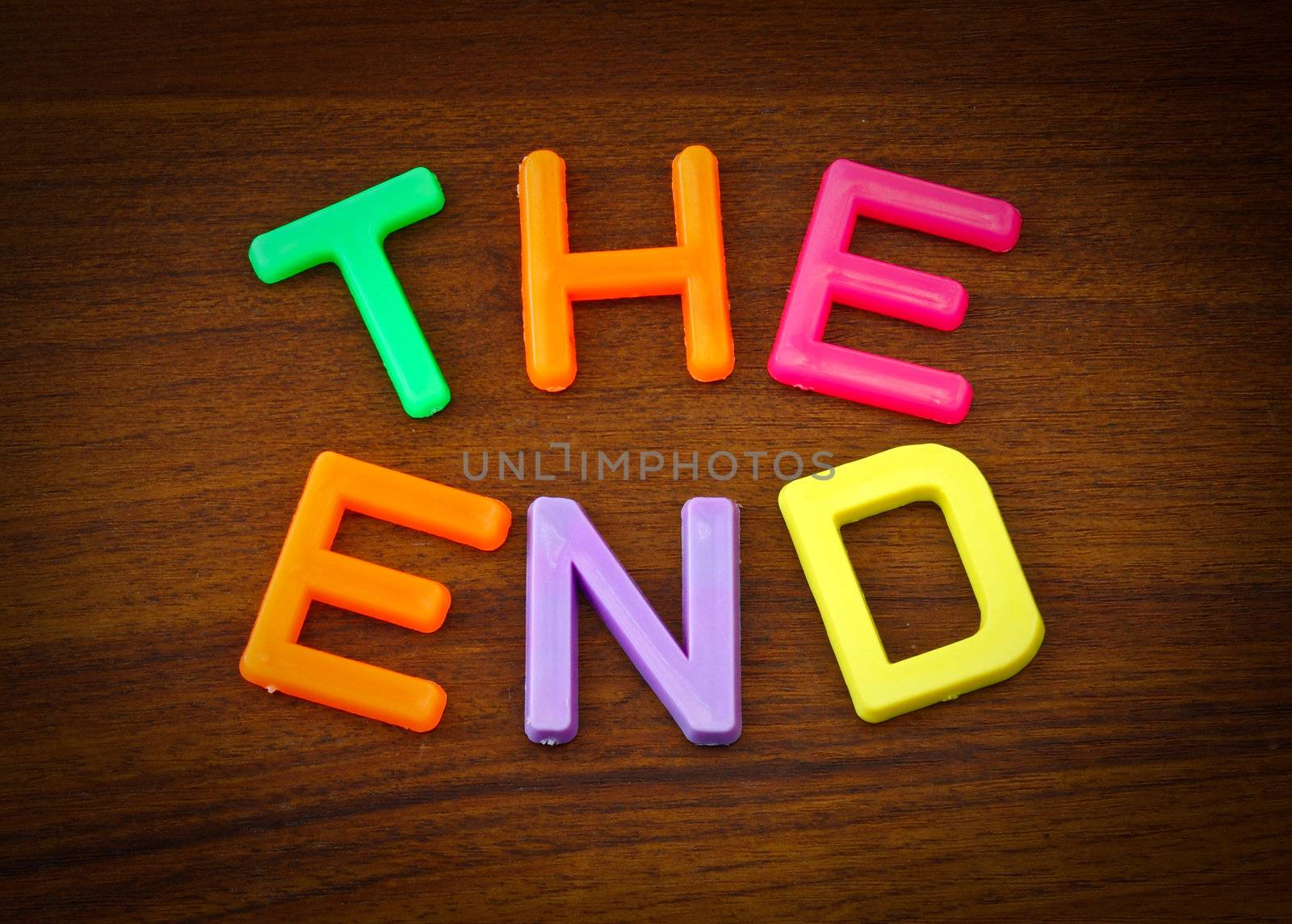 The end in colorful toy letters on wood background by nuchylee