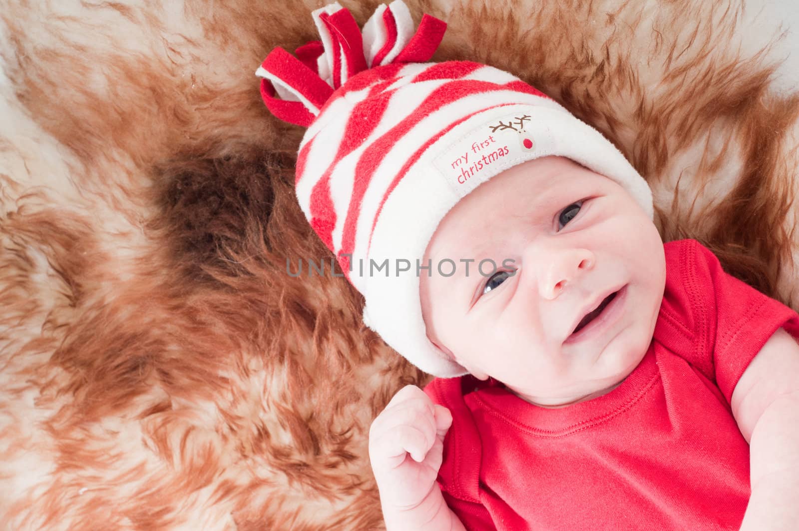 Newborn baby in chritstmas hat lies on fur