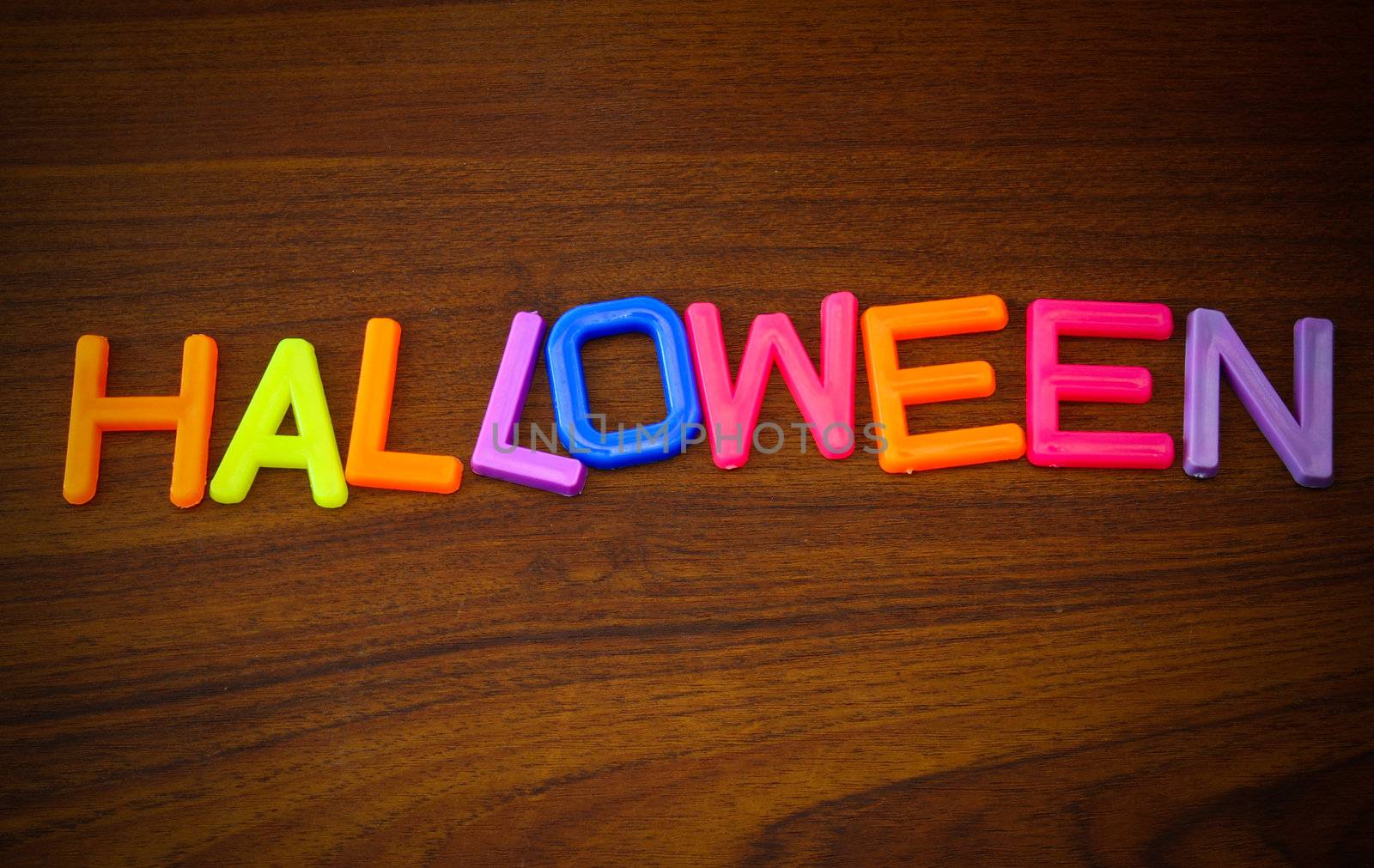 Halloween in colorful toy letters on wood background