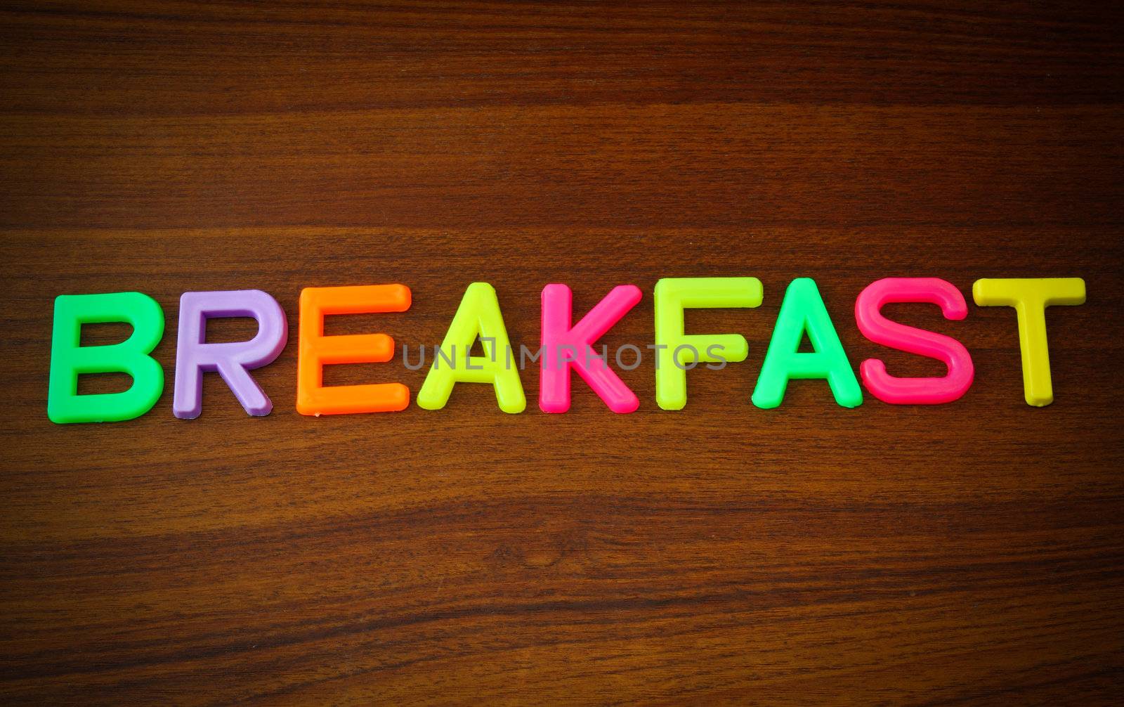 Breakfast in colorful toy letters on wood background