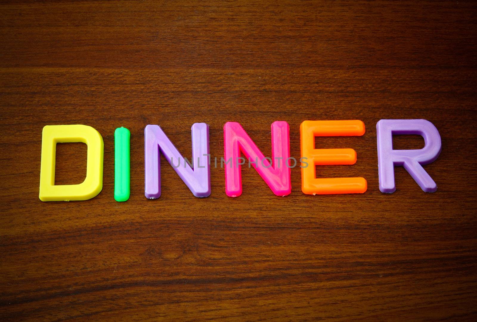 Dinner in colorful toy letters on wood background