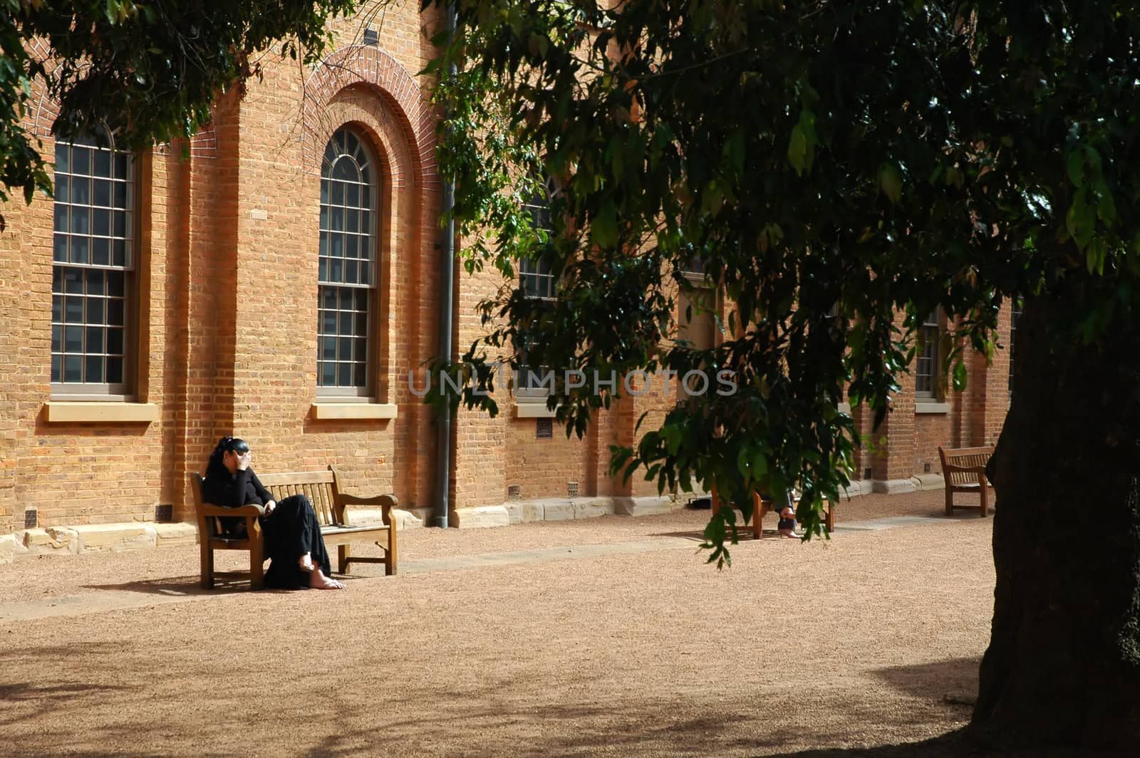 mourning woman sitting on a wooden bench in front of a church