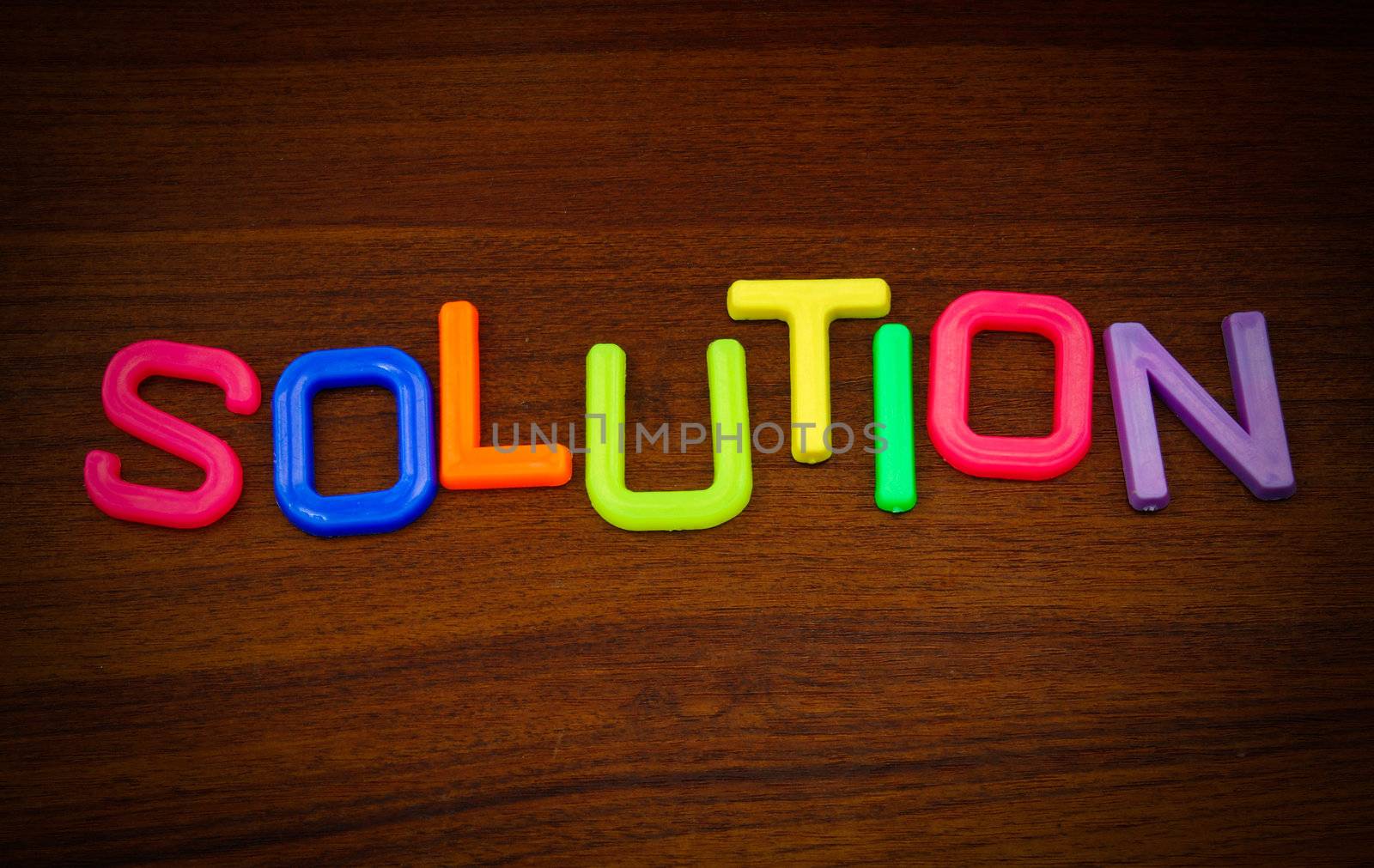 Solution in colorful toy letters on wood background